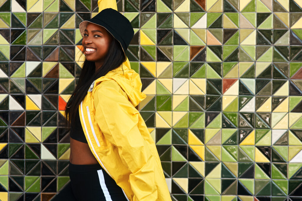 Cropped portrait of an attractive young woman standing alone against a brightly tiled wall during the day