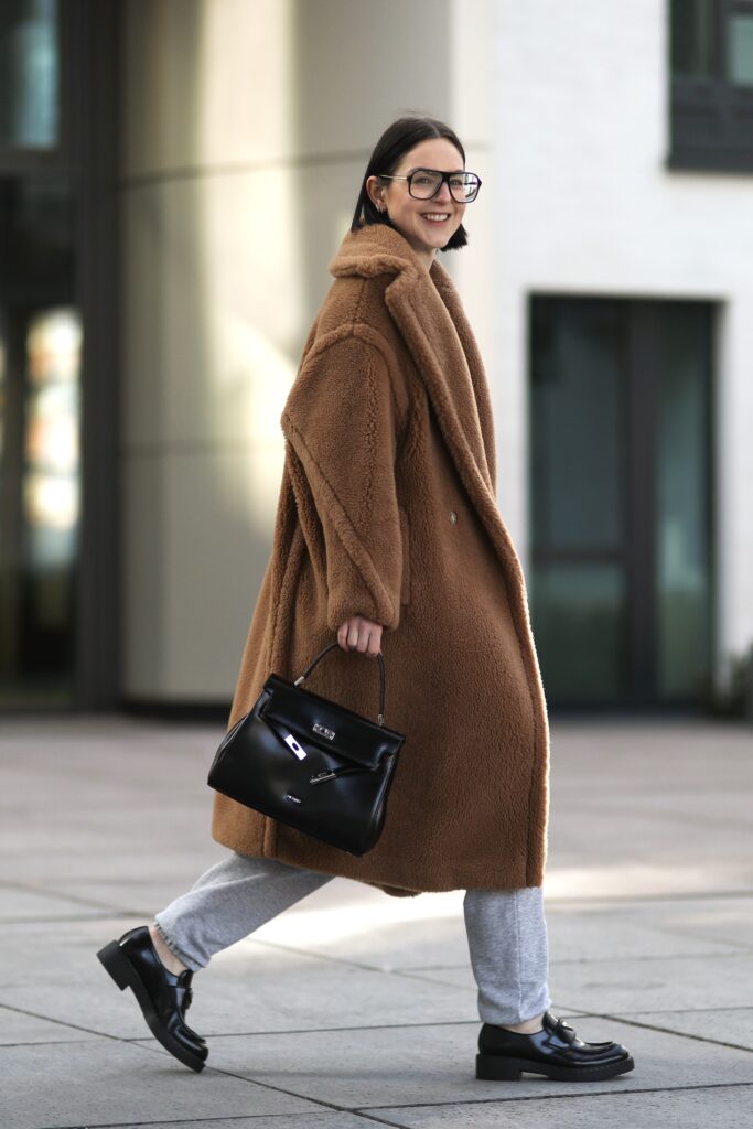 DUSSELDORF, GERMANY - FEBRUARY 27: Maria Barteczko wearing brown Max Mara teddy coat, grey H&M sweater, grey H&M jogging pants, black Prada chunky loafer, black Picard Berlin tote bag and black oversized Victoria Beckham Aviator glasses on February 27, 2021 in Dusseldorf, Germany. (Photo by Jeremy Moeller/Getty Images)