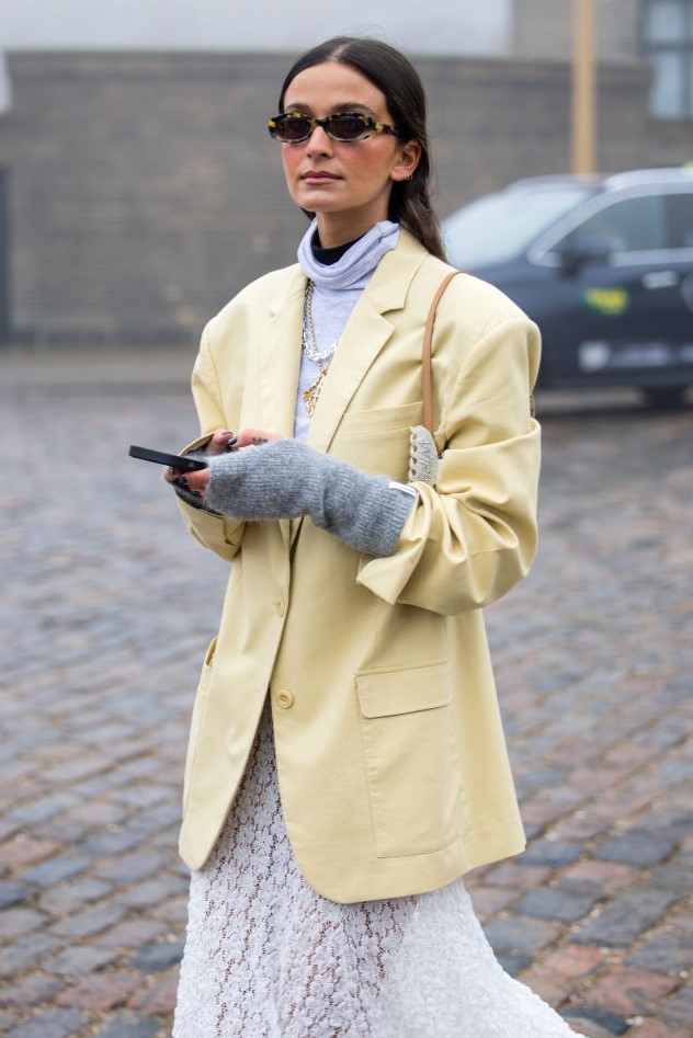 COPENHAGEN, DENMARK - JANUARY 30: A guest wears yellow oversized blazer, white laced skirt, grey turtleneck outside Rolf Ekroth during the Copenhagen Fashion Week AW24 on January 30, 2024 in Copenhagen, Denmark. (Photo by Christian Vierig/Getty Images)