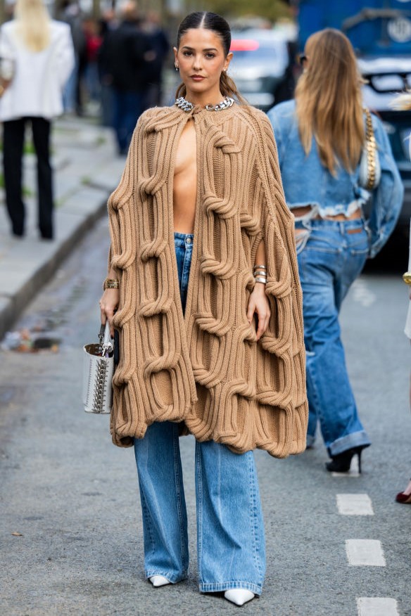 PARIS, FRANCE - SEPTEMBER 30: Paola Alberdi wears beige cut out knitted cape, denim outside Stella McCartney during Womenswear Spring/Summer 2025 as part of Paris Fashion Week on September 30, 2024 in Paris, France. (Photo by Christian Vierig/Getty Images)