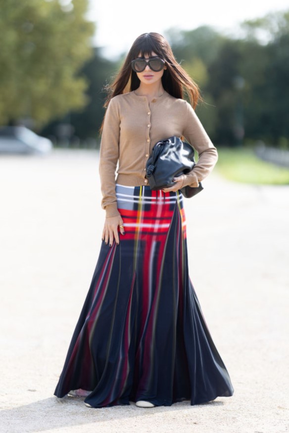 PARIS, FRANCE - SEPTEMBER 27: Deema Al Asadi wears white leather heeled boots, brown sunglasses, a beige cardigan, a black leather pouch bag and a long printed checked skirt outside Loewe show during Womenswear Spring/Summer 2025 as part of Paris Fashion Week on September 27, 2024 in Paris, France. (Photo by Valentina Frugiuele/Getty Images)