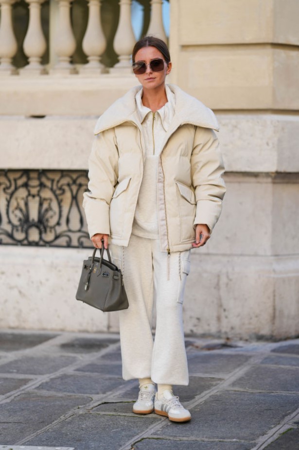 PARIS, FRANCE - OCTOBER 23: Diane Batoukina wears black Dior sunglasses, a white Varley puffer jacket, a white Adidas sweatshirt, white Varley pants, a grey leather Birkin Hermes bag, white socks, white Samba Adidas sneakers shoes, during a street style fashion photo session, on October 23, 2024 in Paris, France.